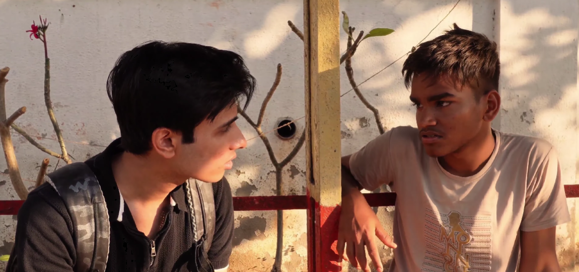 Two young men speaking to one another in a scene from Kshitij.